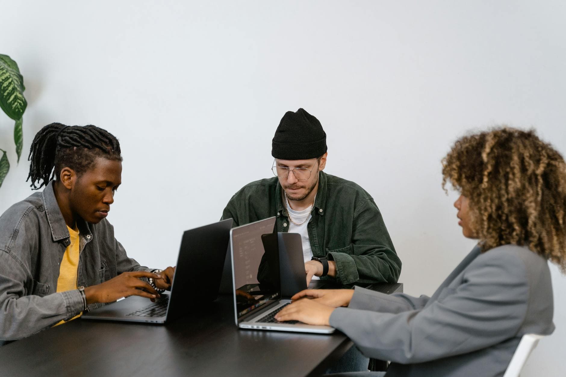 Diverse team of professionals collaborating on laptops